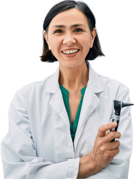 A photo of a dark-haired female audiologist in a white lab coat holding an otoscope with her arms crossed and smiling.