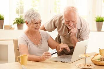 A photo of a male hearing instrument specialist repairing a pair of hearing aids.